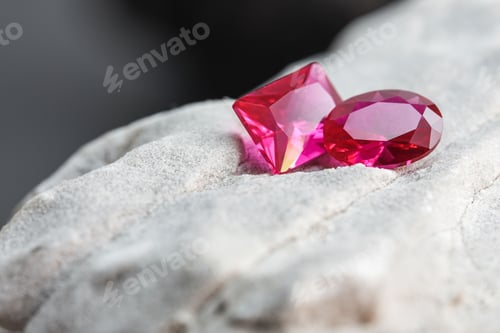 Preview: Glimmering natural pink sapphire gemstones on a rugged rock surface