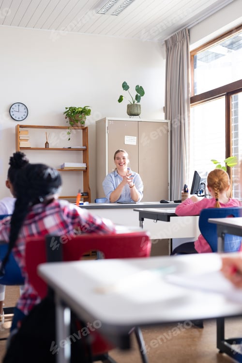 Preview: Female teacher clapping hands, engaging diverse students in classroom during school lesson