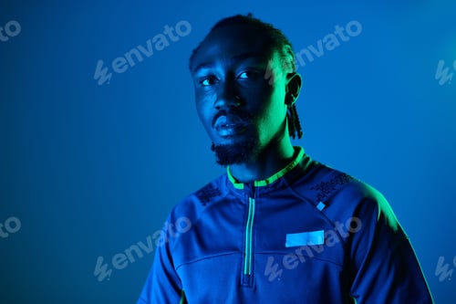 Preview: Stylish young man poses confidently in neon-hued studio setting