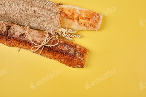 Preview: Top view of two baguette bread on a yellow surface.