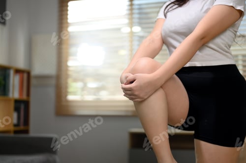 Preview: Cropped shot young woman stretching her legs while exercising at home. Healthy lifestyle concept