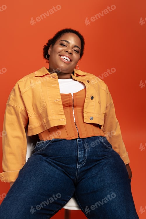 Preview: A stylish plus size woman poses in trendy autumn attire against a vibrant backdrop
