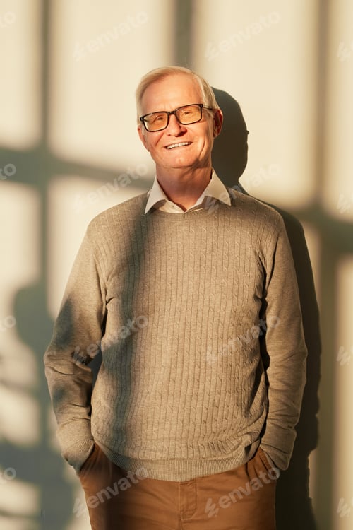Preview: Cheerful senior man in beige pullover standing against wall