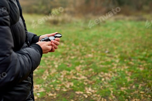 Preview: Traveler man with backpack with compass in hand on a background of mountains of nature