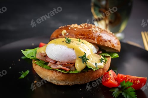 Preview: Breakfast. Sandwich with ham, poached egg, onion and arugula in a plate on a dark background