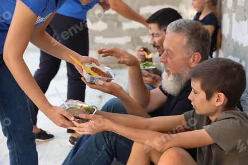 Preview: Poor people receiving food from volunteers near wall outdoors