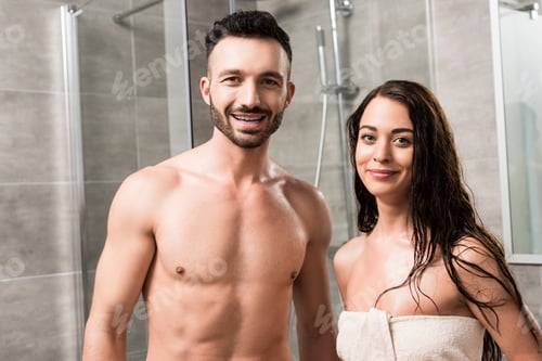 Preview: cheerful bearded man standing with happy brunette woman in bathroom