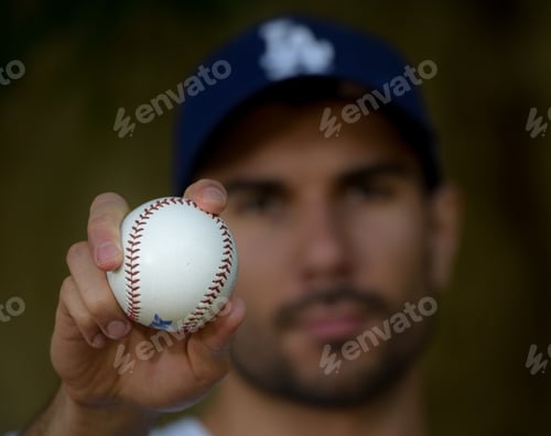 Preview: A man wearing a baseball cap holding a baseball. Depth of field