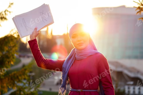 Preview: Arab Muslim business woman hijab with makeup standing on the street holding
