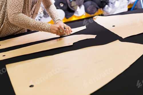 Preview: Hands of mature seamstress chalking shape onto textile on work table