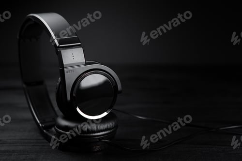 Preview: Black headphones on black wooden dark background.