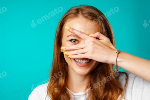 Preview: Happy young woman peeping through her fingers and smiling