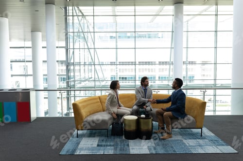 Preview: Business people sitting and discussing with each other in lobby at office