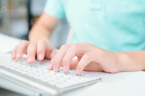 Preview: Human hands pushing keys of computer keyboard while sitting by desk