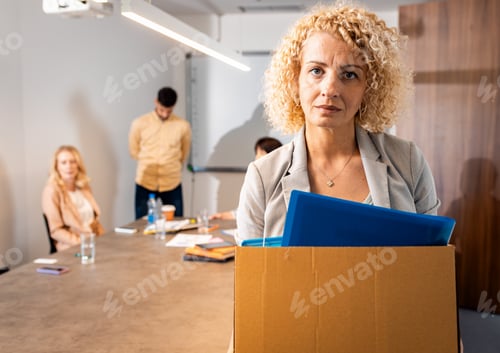 Preview: Portrait of woman holding box of personal belongings being fired from work.