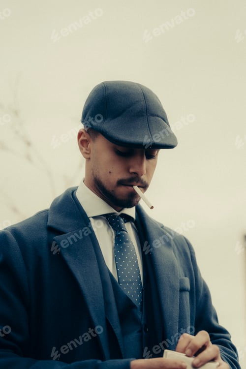 Preview: Vertical shot of a Hispanic male in retro 1900s gangster fashion smoking a cigarette