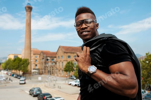Preview: Happy young stylish african man walking at the old town