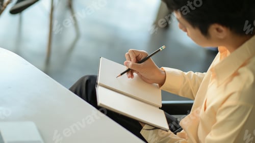 Preview: Young business man is recording the work schedule in the notebook.