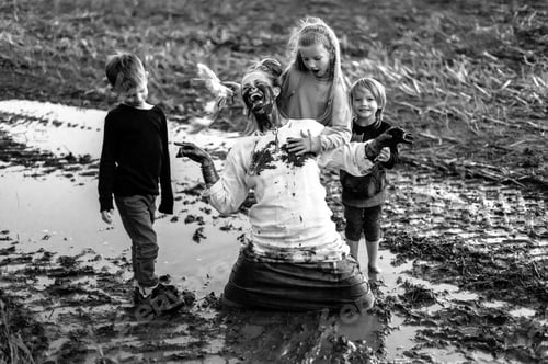 Preview: Happy woman and three children having fun on muddy field