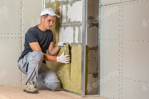 Preview: Worker insulating a room wall with mineral rock wool thermal insulation.