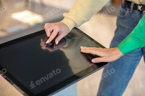 Preview: Female hands touching fingers on the screen of the device.