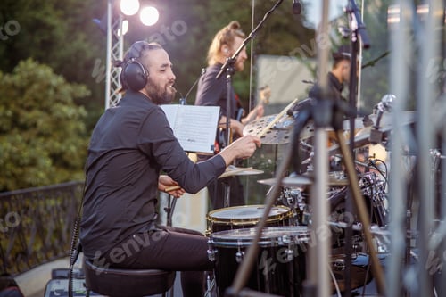 Preview: Cheerful bearded man playing drums at outdoor concert