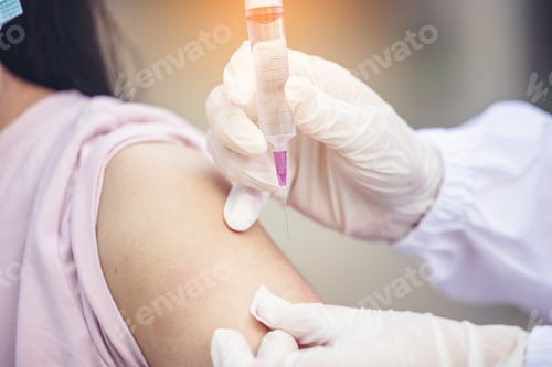 Preview: Female doctor holding syringe making covid 19 vaccination injection dose in shoulder of female patie
