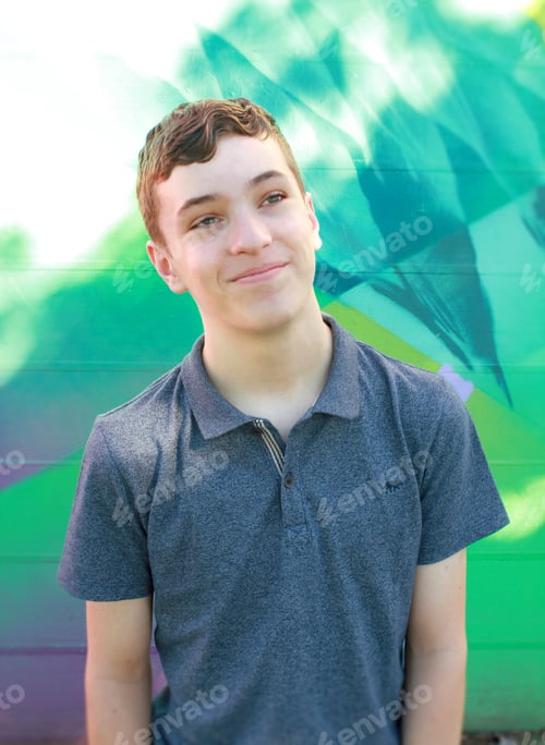 Preview: Happy boy in a polo shirt, smiling with a painted cool toned background behind