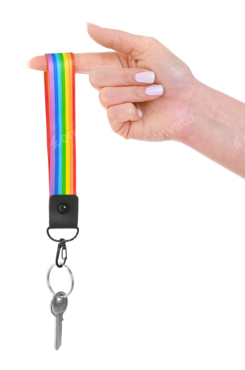 Preview: Woman holding key with keychain in LGBT colors on white background, closeup