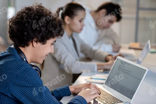Preview: Successful teenage student looking at laptop display while entering information