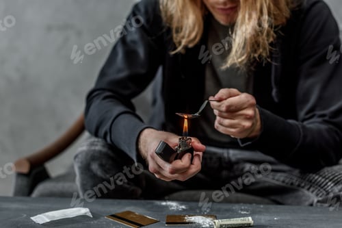 Preview: cropped shot of addicted junkie boiling heroin in spoon with lighter