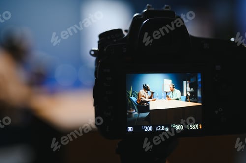 Preview: Focus on the camera filming the men's podcast in a professional podcast studio.