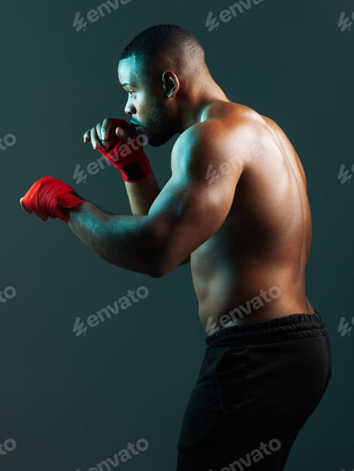 Preview: Stand back, hes about to strike. Shot of a handsome young man boxing against a studio background.