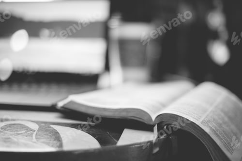 Preview: Grayscale closeup shot of an open bible on the table wit ha blurred background