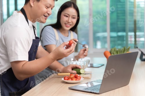 Preview: Cooking with Technology. A couple enjoying a cooking session while using a laptop.