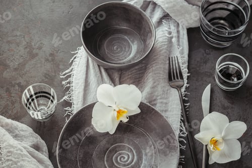 Preview: Elegance table setting with grey napkin, cutlery, ceramic plates, glasses and white orchid flowers
