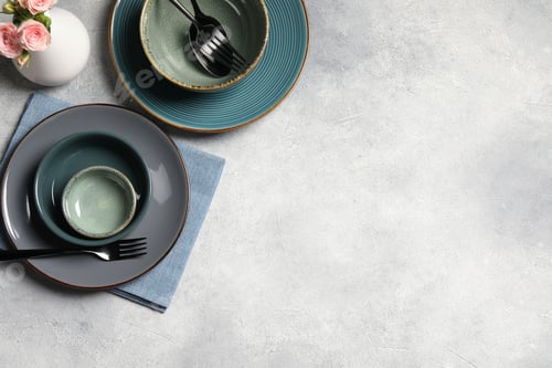 Preview: Stylish tableware and vase with beautiful roses on light grey table, flat lay. Space for text