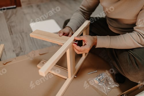 Preview: Skilled man assembles wooden furniture with a hex key