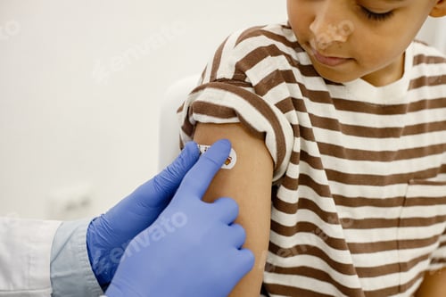 Preview: Cropped photo of male doctor stick a band-aid to a boy after a vaccination