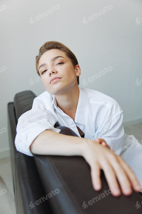 Preview: Women lying at home on the couch portrait with a short haircut in a white shirt, smile, depression