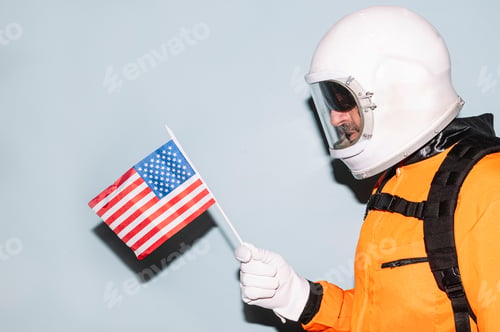 Preview: Man with astronaut helmet looking at the flag of the United States