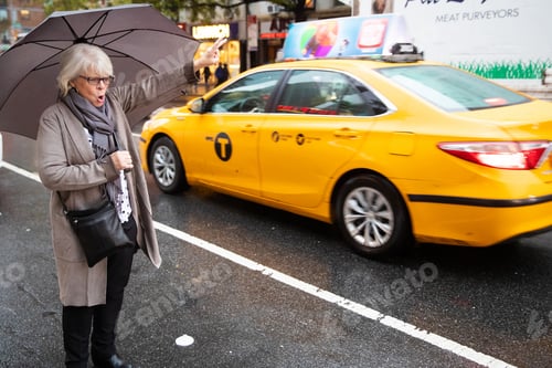 Preview: Mature senior white haired woman waiting for taxi cab in New York