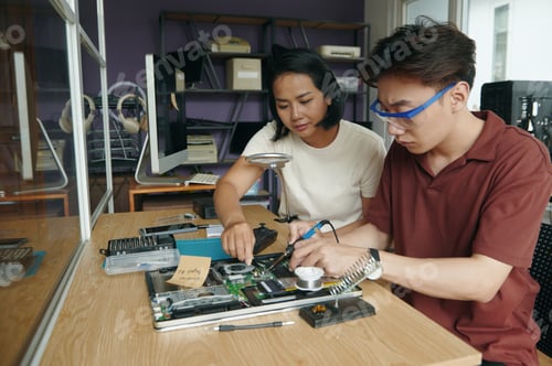 Preview: Colleagues Repairing Laptop Together In Workshop