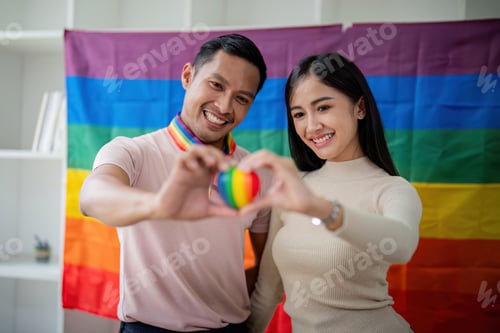 Preview: Young gay male and girl friend hands holding rainbow heart with smile face. LGBT, human rights and