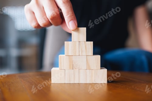 Preview: Closeup image of a hand stacking and picking blank wooden cube block