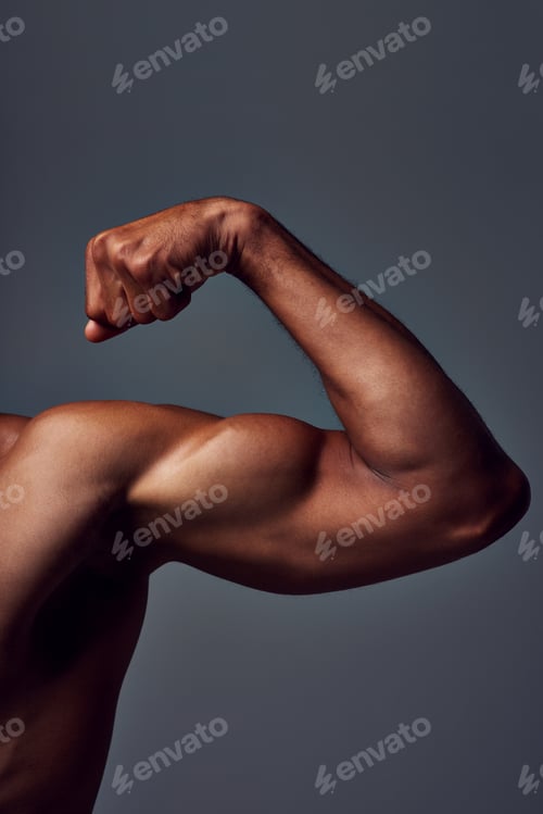 Preview: Studio shot of an unrecognizable muscular sportsman flexing his bicep against a grey background