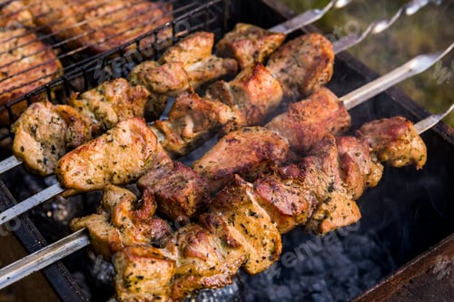 Preview: Grilled kebab cooking on metal skewers. Roasted meat cooked at barbecue