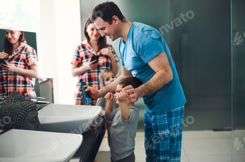 Preview: Caucasian parents and three kids in pajamas having morning routine in bathroom