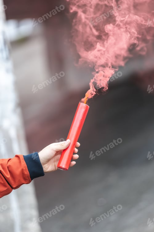 Preview: cropped image of young woman holding red smoke bomb at city street