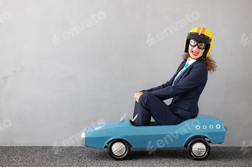 Preview: Successfull businesswoman driving toy car outdoor
